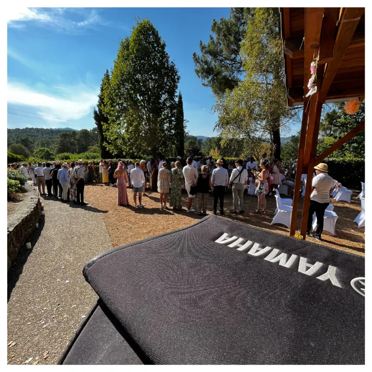 Invités d'un mariage réunis dans un jardin, avec la sonorisation MGK Events au premier plan